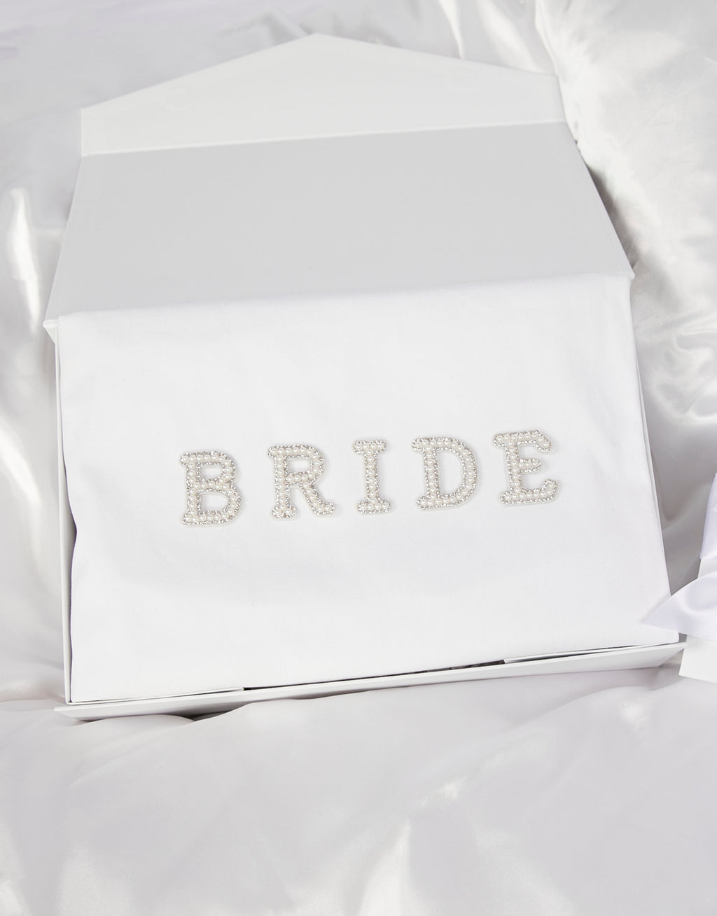 23Dreams Whitehaven Bliss Bridal Box: white tote bag with "bride" pearl and rhinestone patches, 2 petite white gift boxes; one Mini Love hearts Bath Bomb Fizzies; hamptons deluxe candle whitehaven sea salt; ultra soft satin sleep eye mask white; scrunchie soft silky satin white; luxe silky camisole set white; Elegant 18K Gold Plated Letter Pearl Necklace; glamour pearls hair pin set in gold 18 pins; white pearls gold hair pin set luxe glam and white pearled hair clip set in gold timeless elegance.