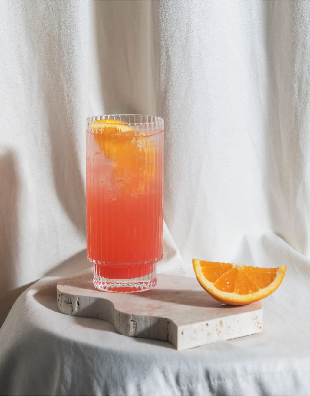 Tall Glass of Aperitif garnished with a slice of orange.